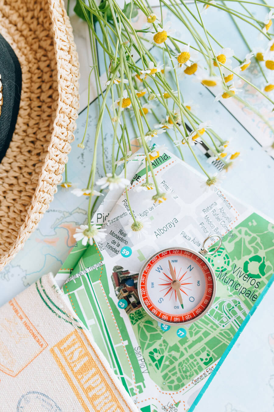 egy asztalon szalmakalap, vadvirágok és egy térkép iránytűvel